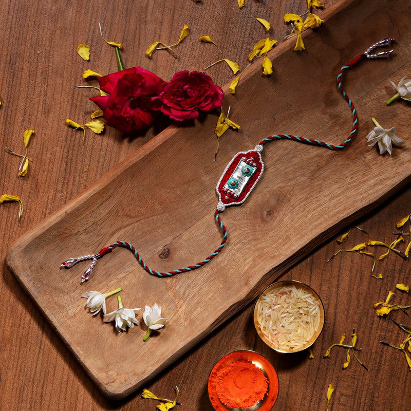 Silver Metal Rakhi With Red Thread Work
