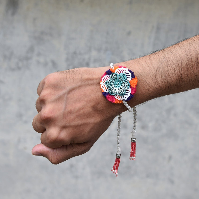 Feroza Metal Flower Rakhi With Magenta, Orange & Purple Fringes