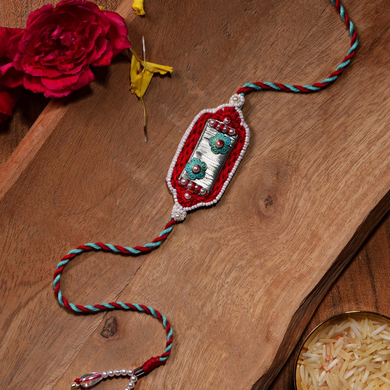 Silver Metal Rakhi With Red Thread Work